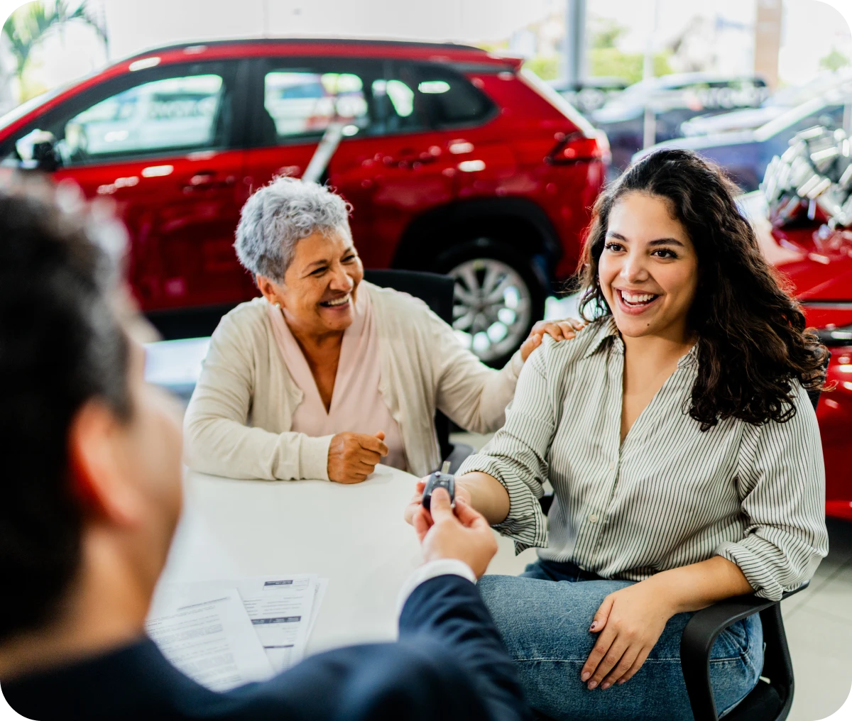 Happy woman receiving car keys at dealership